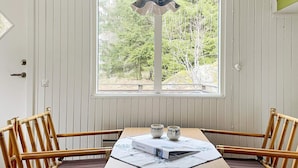A dining area with a table and chairs, a window with a view of trees, and a door with a keyhole.