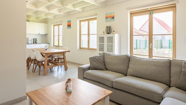 Un salon moderne avec un canapé, une table basse en bois et un coin repas comprenant des chaises et une table.