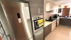 Une cuisine moderne équipée d’appareils électroménagers en acier inoxydable, notamment un réfrigérateur, un four et un lave-vaisselle.
