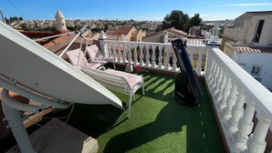 Une terrasse sur le toit dotée d’une balustrade blanche, d’un télescope et de deux fauteuils de relaxation.