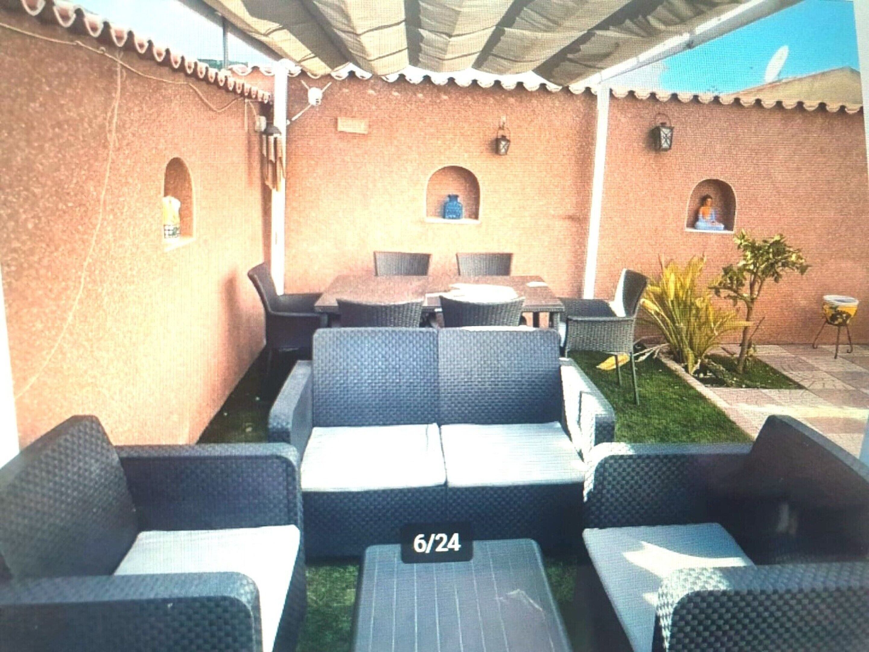 An outdoor seating area with wicker furniture, a brick wall, and a small garden.