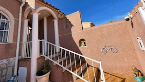 Un bâtiment avec un escalier, une caméra de surveillance et un vélo.