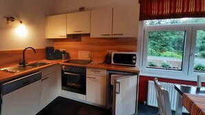 Una cocina compacta con encimera de madera, un fregadero, una estufa, un microondas y un lavavajillas.