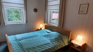 Un dormitorio con una cama, dos lámparas de noche y un ventanal con cortinas.