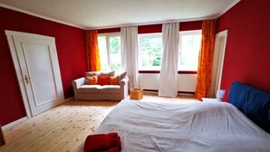 A bedroom with a large bed, a sofa, and a window with curtains. - Sophienhof Lieselotte (Neuenkirchen)