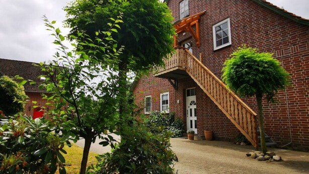 A brick building with a wooden staircase leading to a balcony. - Sophienhof Lieselotte (Neuenkirchen)