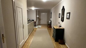 A narrow hallway with wooden flooring, a beige carpet, and a dresser with drawers. - Sophienhof Lieselotte (Neuenkirchen)