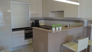 Una cocina moderna con una isla central, horno empotrado y armarios blancos.