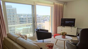 Una sala de estar moderna con un sofá, sillones, una mesa de centro y un televisor.