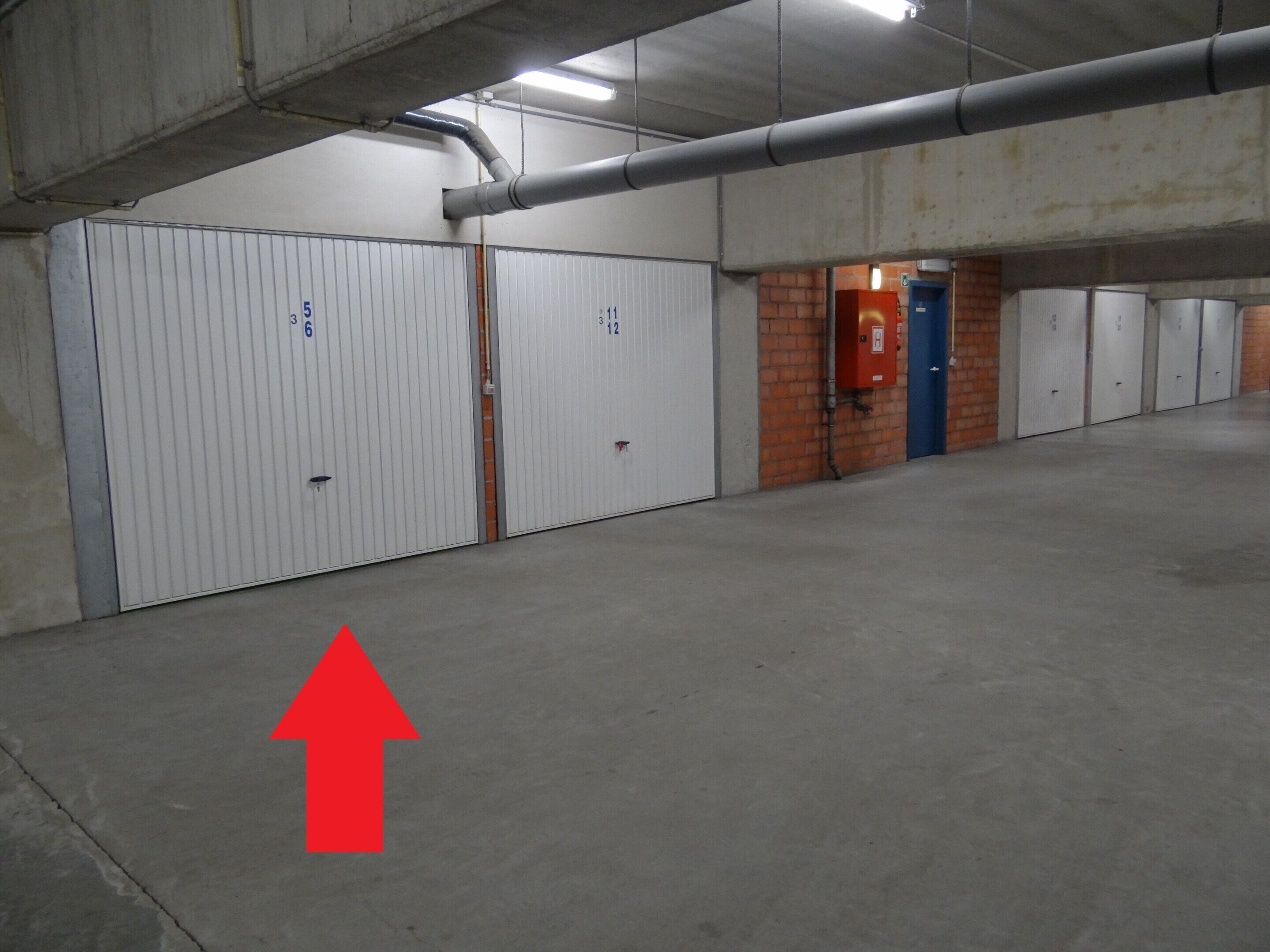 A parking garage with numbered parking bays, a fire extinguisher, and a blue door.