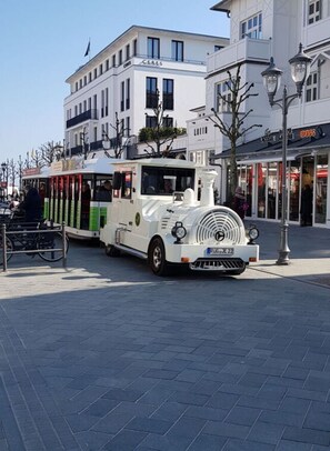 Een witte tram met een klassiek ontwerp, geparkeerd op een verharde straat met gebouwen op de achtergrond.