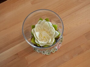 Een glazen schaal met een witte bloem op een houten ondergrond.