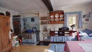 A cozy kitchen with wooden cabinets, a blue tiled backsplash, and a dining area with a pink table and blue chairs. - The Holler Comfortable Holiday Residence (Schwanberg)