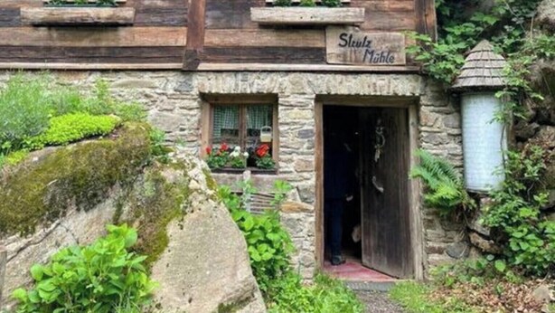A rustic wooden house with a stone foundation, two windows with flower boxes, and a sign reading "Schloss Mühle". - The Holler Comfortable Holiday Residence (Schwanberg)