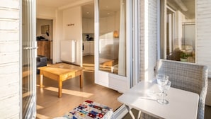 Ein modernes Interieur mit Essbereich, Küche und einem Balkon mit Korbmöbeln.