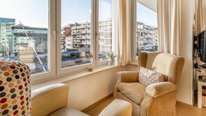 Ein modernes Wohnzimmer mit großem Fenster, einer Couch und einem Fernseher.