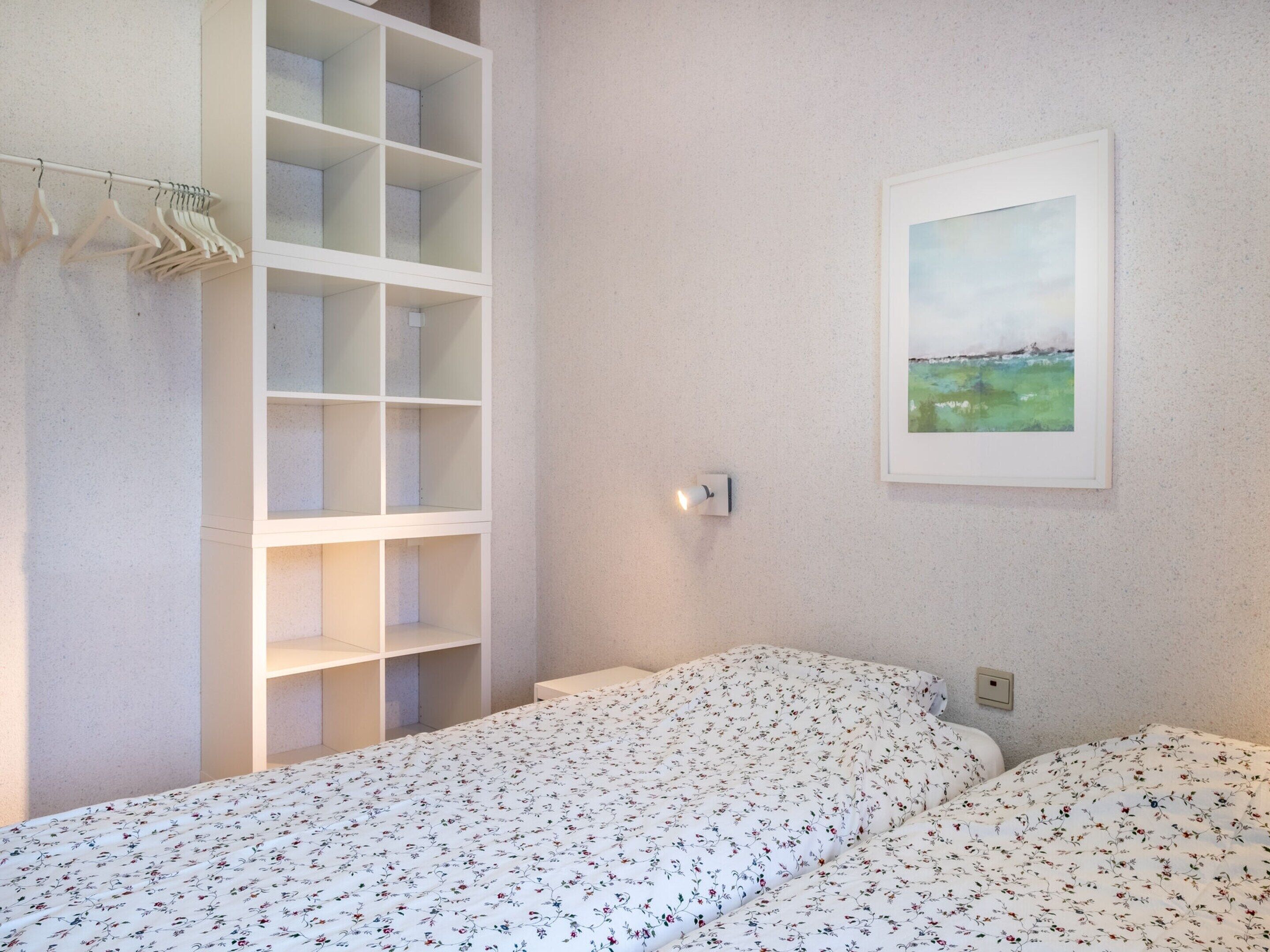 Ein Schlafzimmer mit einem Bett, einem Kleiderschrank und einem gerahmten Bild an der Wand.