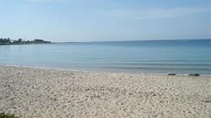 A beach with a sandy shore and calm water. - Topazio Comfortable Holiday Residence (Quartu Sant'Elena)
