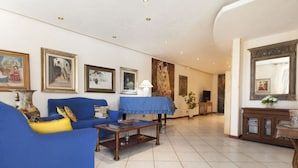 A living room with a blue sofa, a coffee table, and a TV. There are framed pictures on the wall and a mirror above the TV. - Topazio Comfortable Holiday Residence (Quartu Sant'Elena)