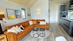 Ein modernes Wohnzimmer mit einer Eckcouch, einem runden Couchtisch und einer Küchenzeile mit Spüle und Schränken.