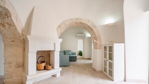 A hallway with a stone fireplace, a sofa, and a cabinet. - Villa 'I Trulli Di Ninì' with Private Pool, Wi-Fi and Air Conditioning (martina franca)