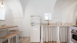 A compact kitchen with a white refrigerator, a sink, a wooden bench, and a window. - Villa 'I Trulli Di Ninì' with Private Pool, Wi-Fi and Air Conditioning (martina franca)
