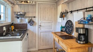 A compact kitchen with a sink, a coffee maker, and a wooden table. - 2 Person Holiday Home in Bello (Hjältevad)