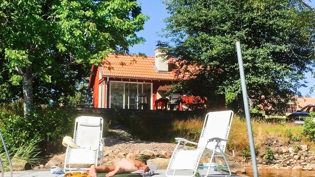 A swimming pool with lounge chairs and a person lying on a lounge chair. - 2 Person Holiday Home in Bello (Hjältevad)