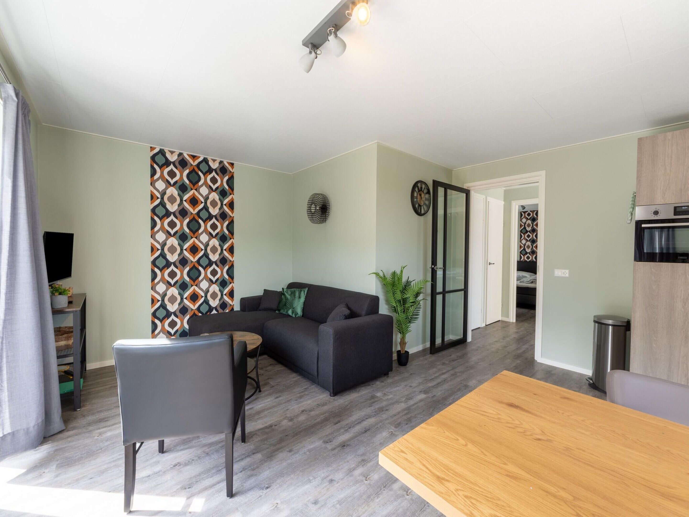 Un salon moderne comprenant un canapé, une table à manger et un coin cuisine avec un four.
