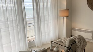 A modern living room with a view of the beach, a lamp, and a laptop on a table. - Apartment in Nieuwpoort for 6 Persons (Nieuwpoort)