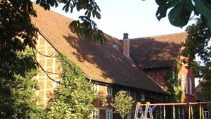 A brick house with a red-tiled roof, a swing set, and a ladder. - The Large Holiday Apartment (Wölpinghausen)