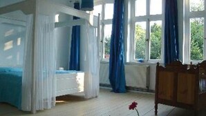 A room with a four-poster bed, a wooden chair, and a vase with a flower. - The Large Holiday Apartment (Wölpinghausen)