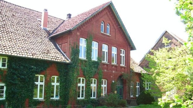 A red brick building with a tiled roof, ivy-covered walls, and multiple windows. - The Large Holiday Apartment (Wölpinghausen)