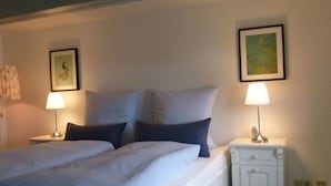 A double bed with white bedding and two pillows, flanked by white nightstands with lamps. There are framed pictures on the walls. - Stadthaus Emmy Marxen (Schleswig)