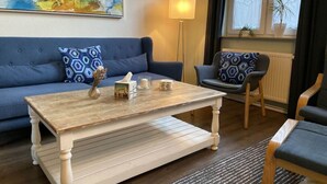 A living room with a blue sofa, a wooden coffee table, and a patterned armchair. - Stadthaus Emmy Marxen (Schleswig)