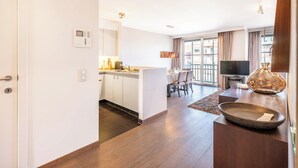 Ein modernes Hotelzimmer mit Küche, Essbereich und Wohnbereich.