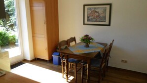 Un coin repas avec une table en bois, des chaises, un vase de fleurs et un tableau accroché au mur.