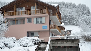 A multi-story building with a wooden balcony, a sign indicating a restaurant, and a snow-covered landscape. - Spacious Retreat, Cavalese (Cavalese)