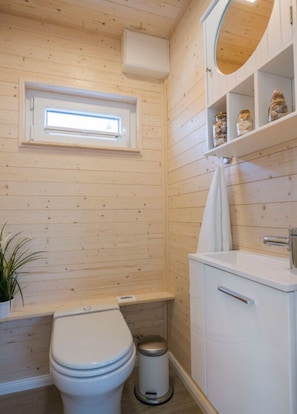A compact bathroom with a toilet, sink, and a small window. - Antje Frieda Comfortable Holiday Residence (Fehmarn)