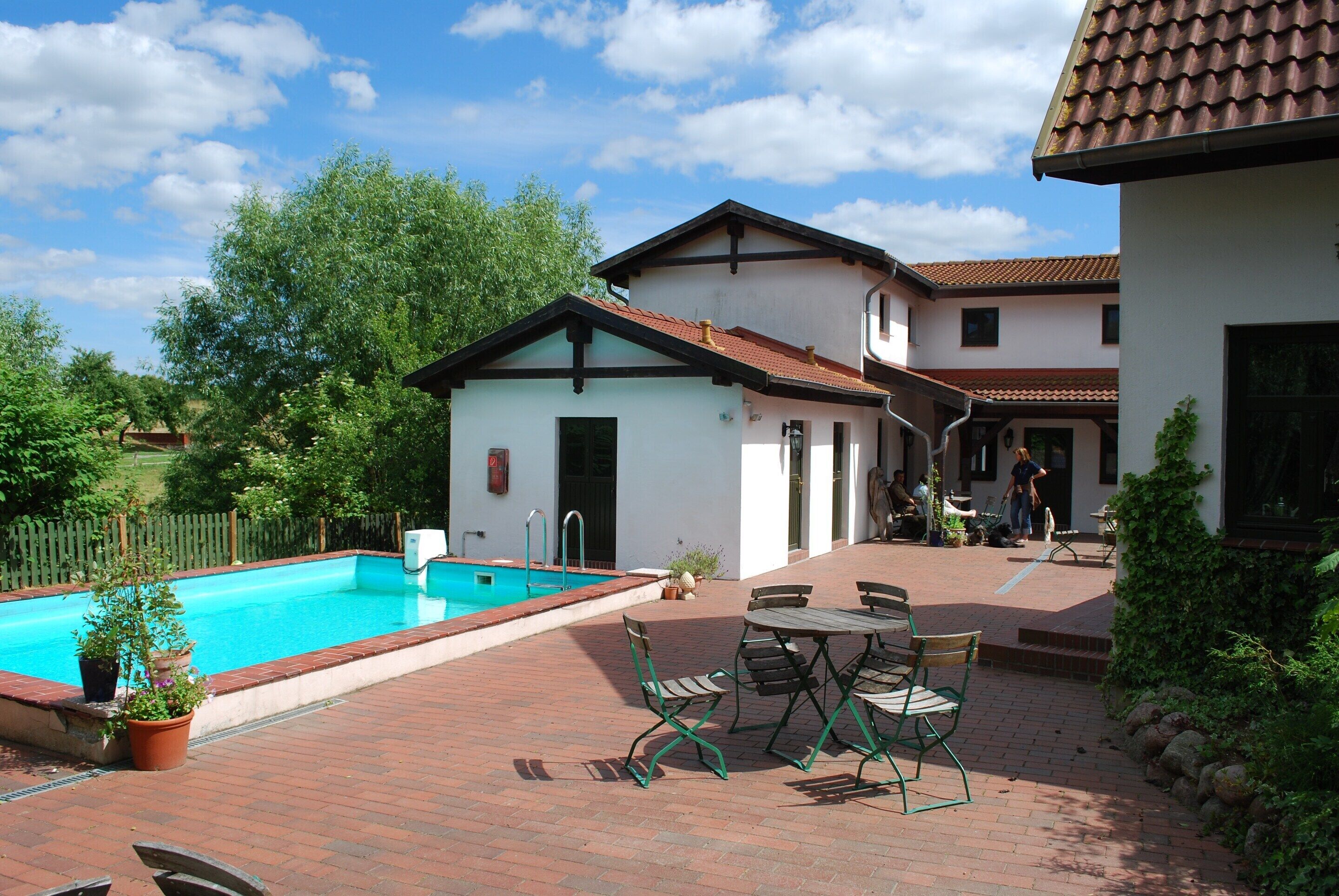 Una piscina con patio de ladrillo y zona de estar al aire libre.