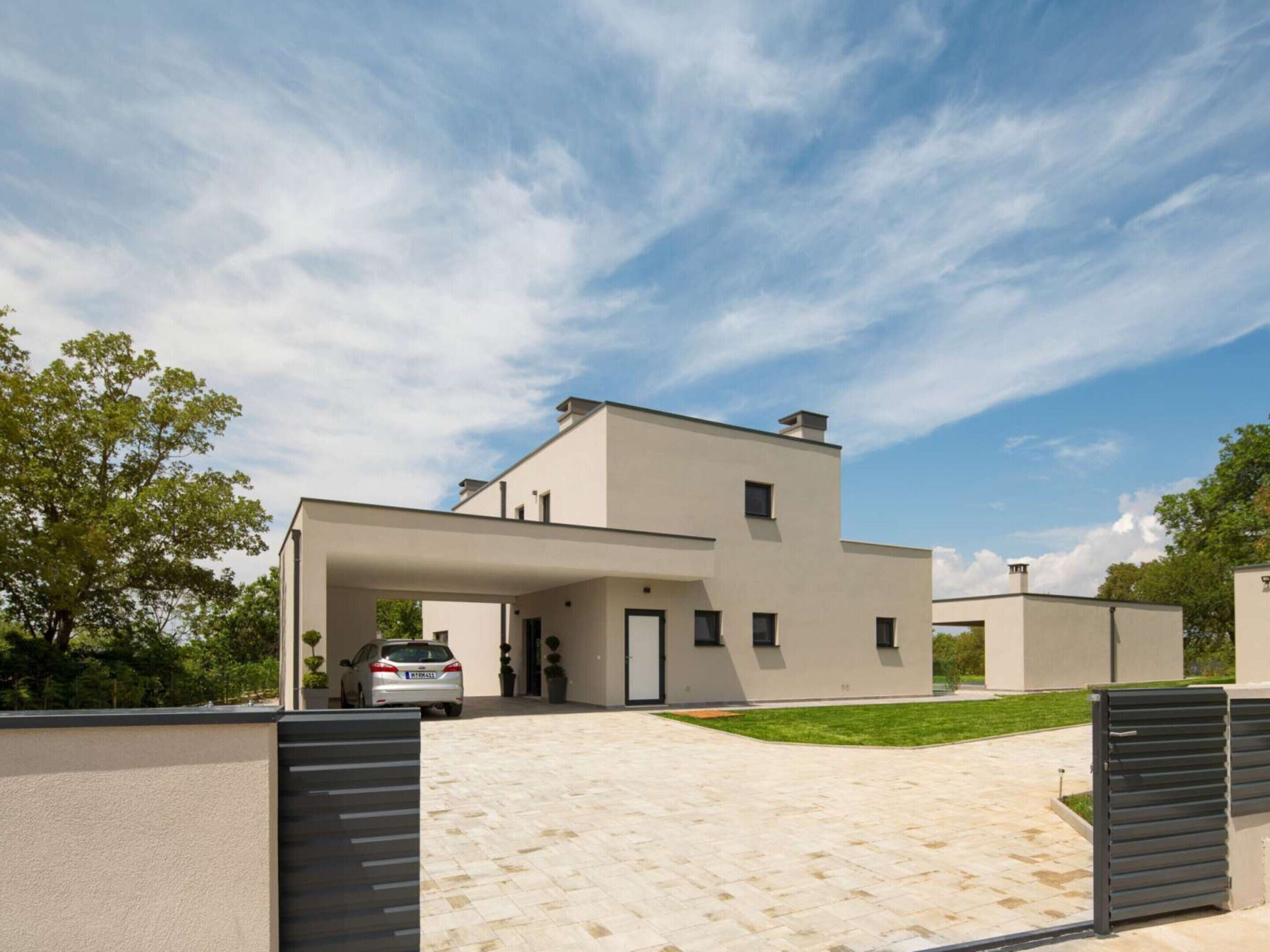 A modern two-story house with a covered driveway and a car parked inside.
