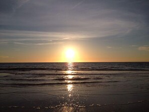 A beach at sunset with the sun reflecting on the water. - Country Life Comfortable Holiday Residence (t Zand)