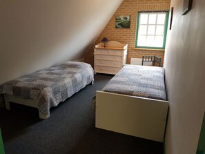 A small, single-room bedroom with two single beds, a dresser, and a window with a view of a green landscape. - Country Life Comfortable Holiday Residence (t Zand)