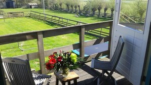 A balcony with two chairs, a small table, and a vase of flowers. - Country Life Comfortable Holiday Residence (t Zand)
