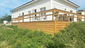 A two-story white house with a wooden deck.