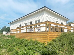 A two-story white house with a wooden deck. - 5 Star Holiday Home in Borgholm (Borgholm)