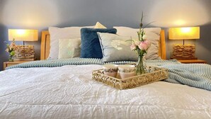 A neatly made bed with a decorative tray, pillows, and a vase of flowers. - Holiday Home Reimers (Windeby)
