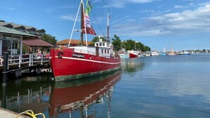 A red boat docked at a marina with a clear sky and calm water. - Holiday Home Reimers (Windeby)