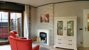 Un salon avec un fauteuil rouge, un meuble blanc et une cheminée.