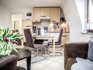 A compact kitchen with modern appliances, a dining area with two chairs, and a cozy living space with a sofa and a table. - "weinberg Uitzicht" in het Felix Huis (Radebeul)